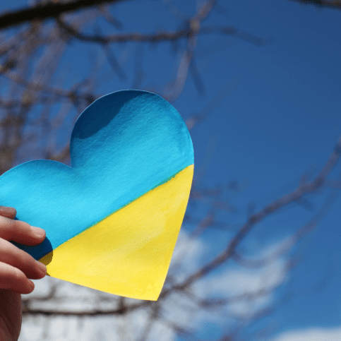 Eine Person hält ein Herz in die Luft, das die Farben der ukrainischen Flagge hat.